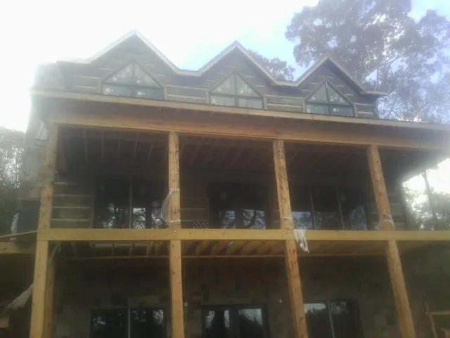 Dormers and porch framing on a large log home under construction — Roof Coating work by our crew in Farley