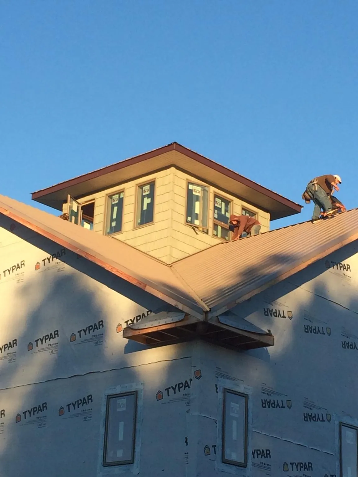 Roofers working around a rooftop cupola on a new metal roof at sunset — Roof Waterproofing in Farley by Roofing Brothers